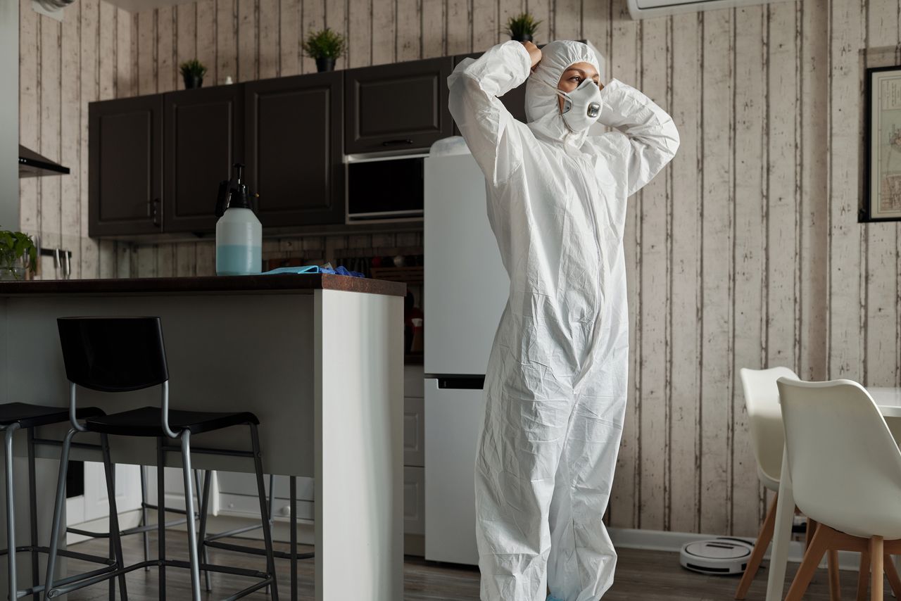 vision Individual in protective gear standing in a contemporary kitchen setting during the day.