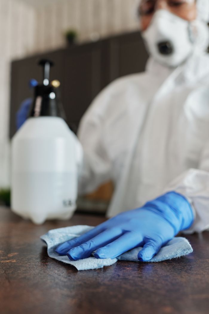 journey-01 Close-up of a professional in full protective gear disinfecting a surface indoors.